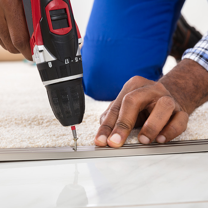 man with a drill repairing a carpet meridian id